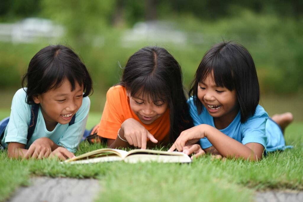 group children lying reading grass field