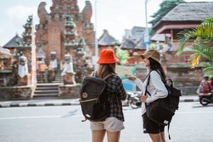 two backpacker girls chat while using map front religious tourism temple